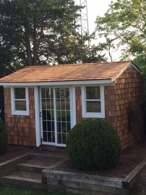 small house made of bricks with two windows and one large glass sliding door