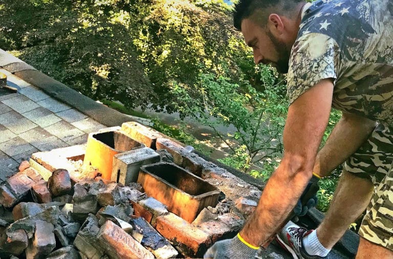 contractor cleaning debris on top of roof